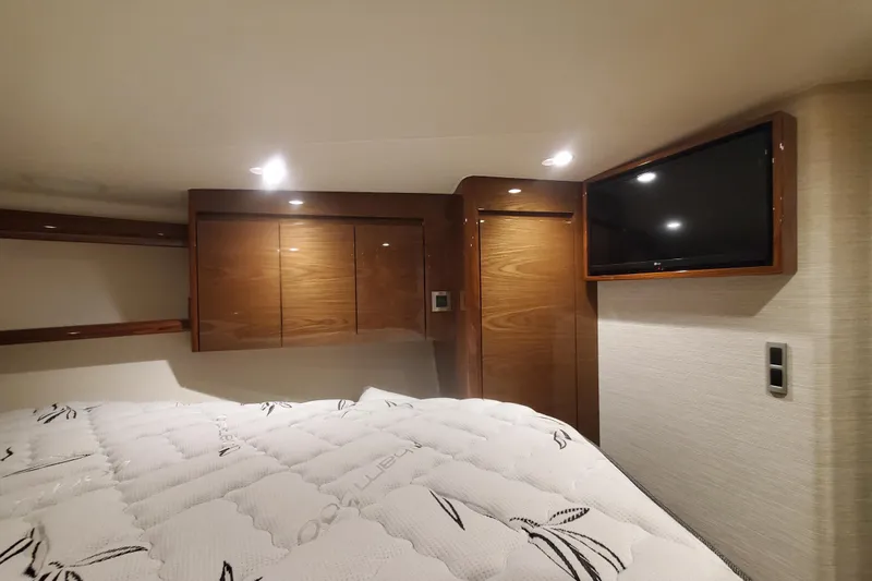 Salty Soul Yacht Photos Pics 2023 Viking 48 Sport Tower cabin interior with bed, wooden cabinets, and wall-mounted TV.