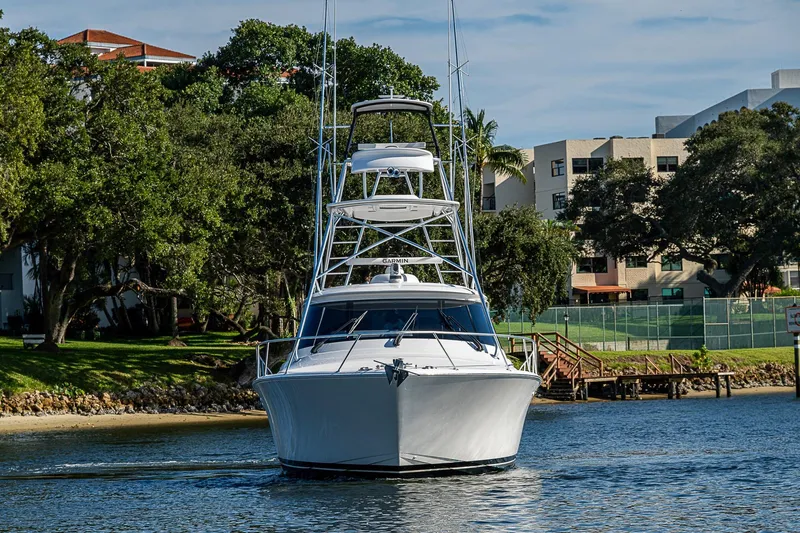 Salty Soul Yacht Photos Pics 2023 Viking 48 Sport Tower yacht cruising near shoreline with trees and buildings.