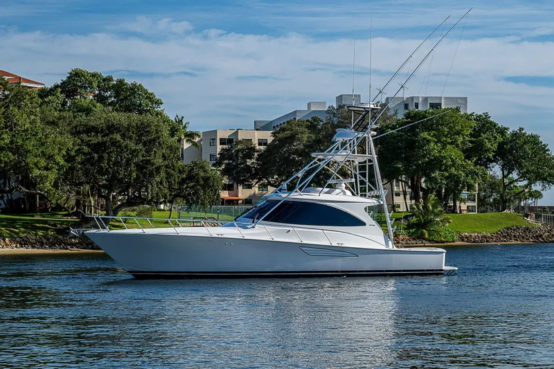 Salty Soul Yacht Photos Pics 2023 Viking 48 Sport Tower yacht on calm water, surrounded by lush greenery.