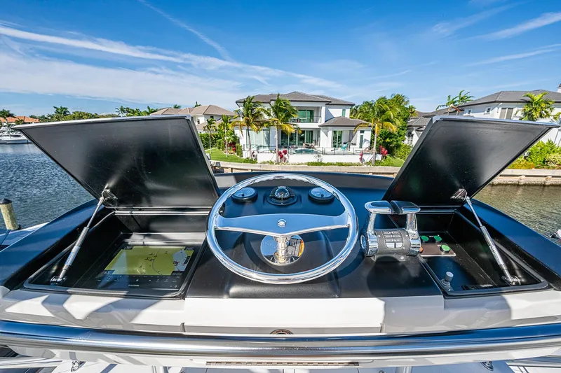 Salty Soul Yacht Photos Pics 2023 Viking 48 Sport Tower helm with navigation screens and controls, docked near waterfront homes.