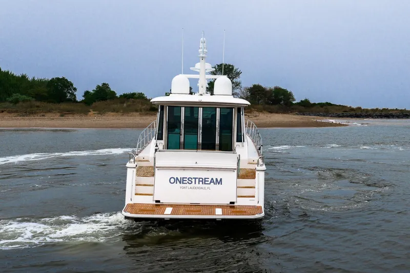  Yacht Photos Pics 2024 Sabre 58 Salon Express yacht cruising near a sandy shoreline.