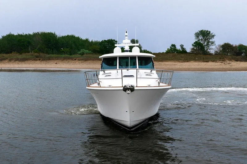  Yacht Photos Pics 2024 Sabre 58 Salon Express yacht cruising near a sandy shoreline.