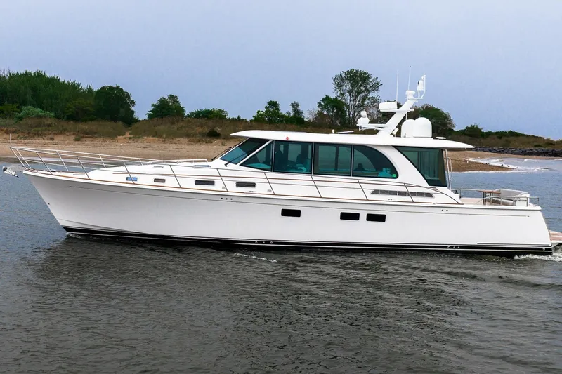  Yacht Photos Pics 2024 Sabre 58 Salon Express yacht cruising near a sandy shoreline.