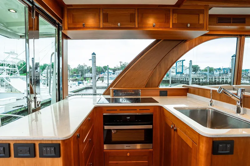  Yacht Photos Pics Luxurious 2024 Sabre 58 Salon Express yacht kitchen with wood cabinetry and marina view.