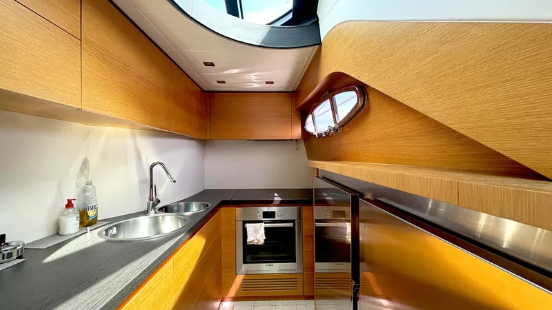 Dolce Vita Yacht Photos Pics Modern kitchen interior on 2011 Pershing 74 yacht, featuring wood cabinetry and stainless steel appliances.