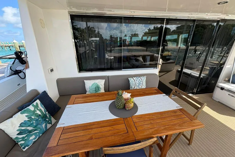 Silent Seven Yacht Photos Pics Outdoor dining area on a 2020 Silent 55 yacht with wooden table and tropical decor.