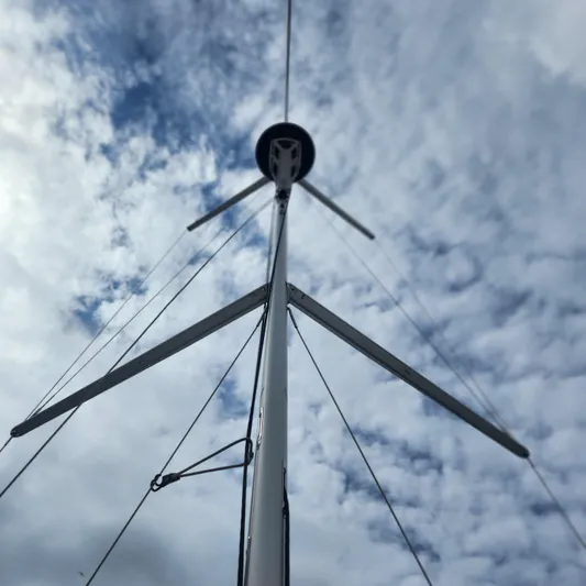 Skye Yacht Photos Pics Mast of 2023 Jeanneau Sun Odyssey 349 sailboat against a cloudy sky.
