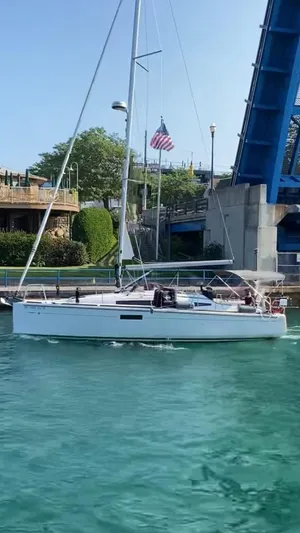Skye Yacht Photos Pics 2023 Jeanneau Sun Odyssey 349 sailing near a bridge on clear blue water.