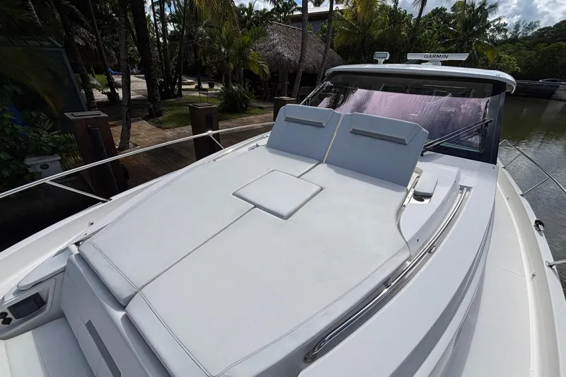  Yacht Photos Pics 2024 Pursuit OS 445 Offshore yacht with spacious sun deck, docked near tropical foliage.