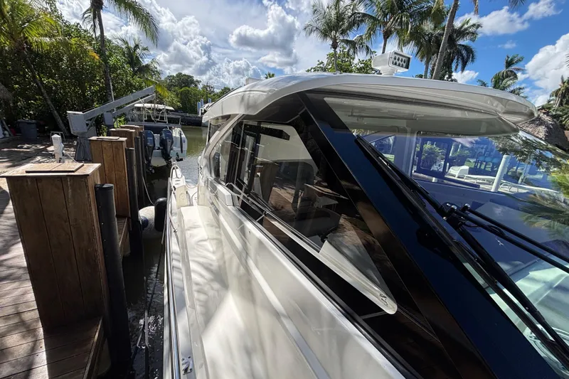  Yacht Photos Pics 2024 Pursuit OS 445 Offshore yacht docked, surrounded by tropical palm trees and clear skies.