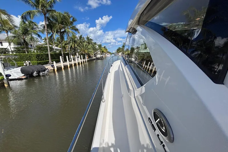  Yacht Photos Pics 2024 Pursuit OS 445 Offshore yacht cruising along a scenic, palm-lined waterway.