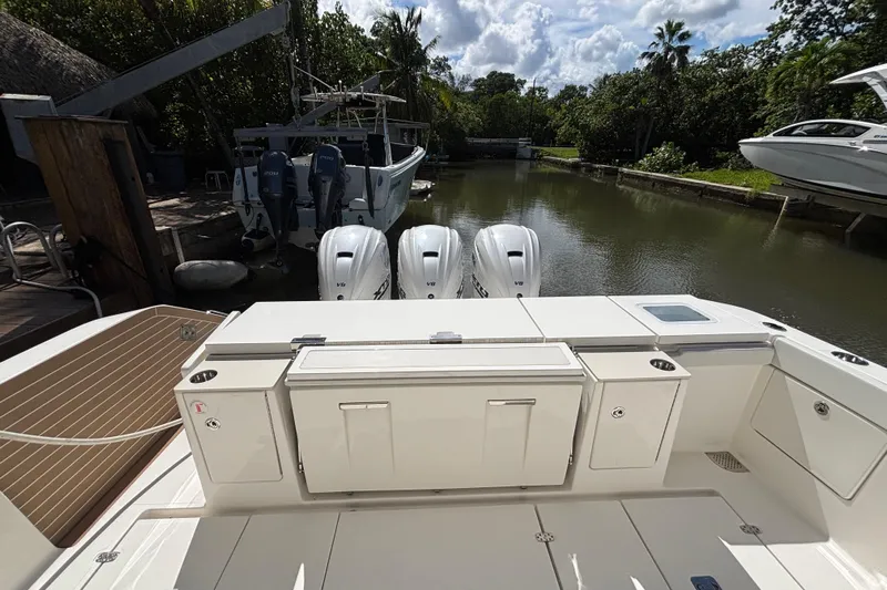  Yacht Photos Pics 2024 Pursuit OS 445 Offshore boat with triple outboard engines docked in a serene canal.