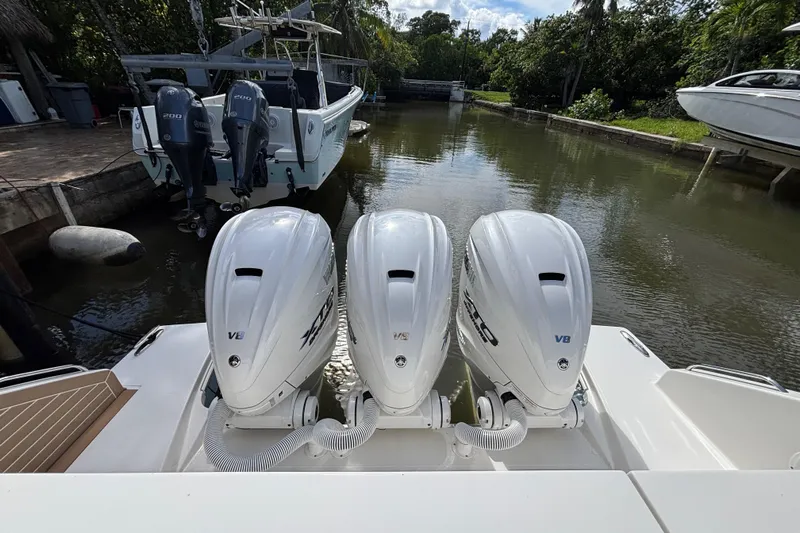  Yacht Photos Pics 2024 Pursuit OS 445 Offshore with triple V8 outboard engines docked in a serene canal.