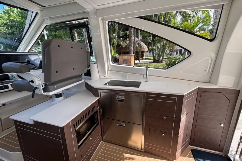  Yacht Photos Pics 2024 Pursuit OS 445 Offshore interior with helm seat, kitchenette, and modern cabinetry.