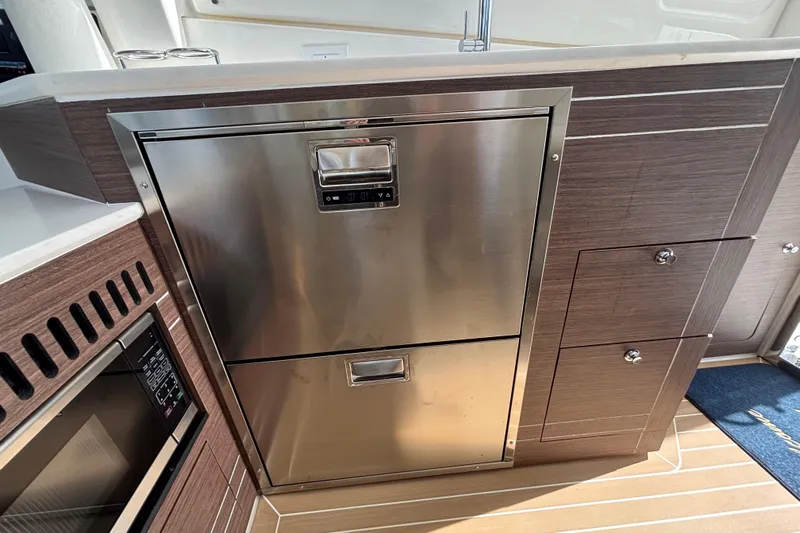  Yacht Photos Pics 2024 Pursuit OS 445 Offshore yacht kitchen with stainless steel appliances and wood cabinetry.