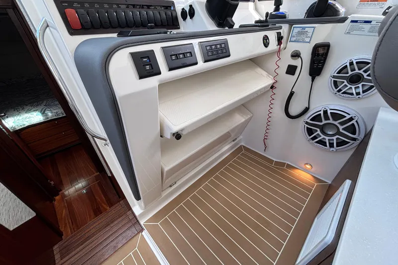  Yacht Photos Pics 2024 Pursuit OS 445 Offshore boat interior with control panel, speakers, and wooden flooring.