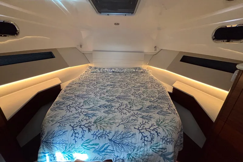  Yacht Photos Pics 2024 Pursuit OS 445 Offshore cabin with a cozy bed and ambient lighting.