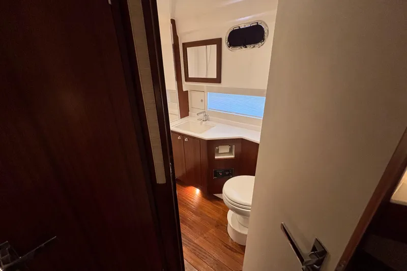  Yacht Photos Pics 2024 Pursuit OS 445 Offshore yacht bathroom with wooden cabinetry and modern fixtures.