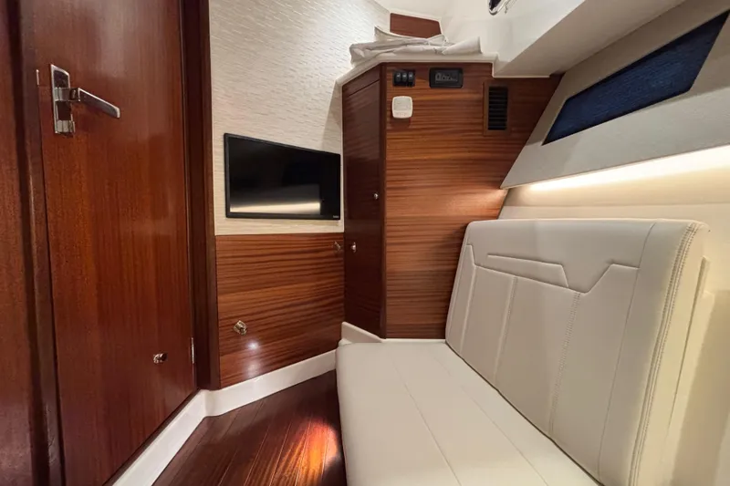  Yacht Photos Pics 2024 Pursuit OS 445 Offshore cabin interior with wood paneling and modern seating.