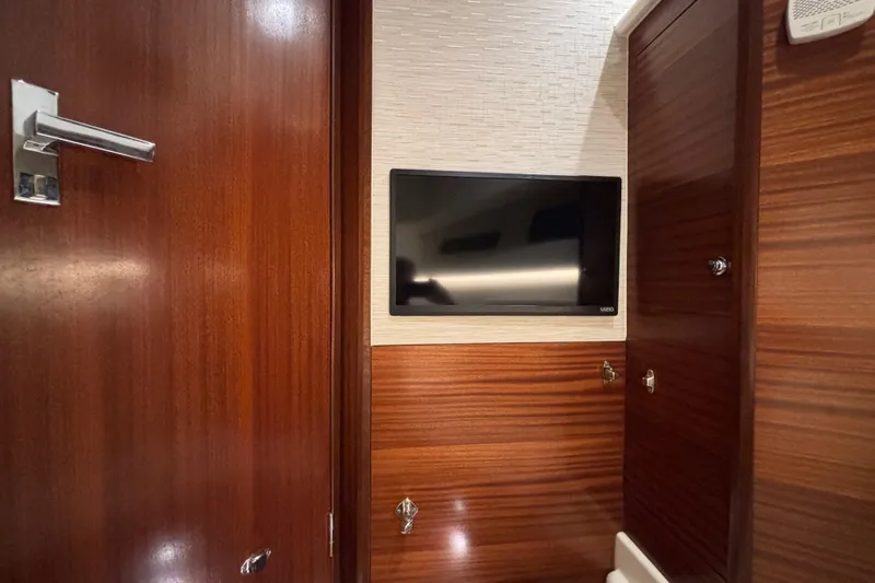  Yacht Photos Pics 2024 Pursuit OS 445 Offshore cabin interior with mounted TV and wooden finish.