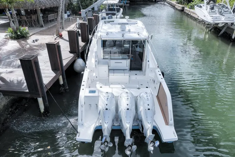  Yacht Photos Pics 2024 Pursuit OS 445 Offshore boat docked, featuring triple outboard engines.