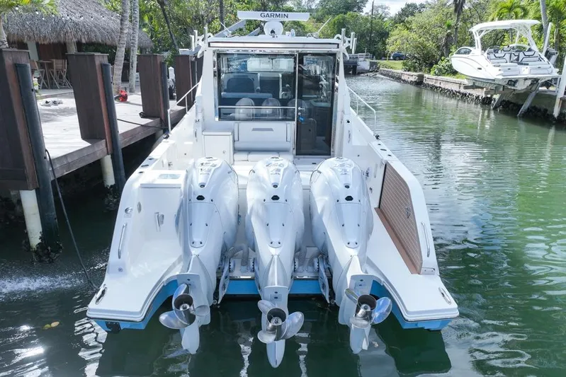  Yacht Photos Pics 2024 Pursuit OS 445 Offshore boat with triple outboard engines docked in a serene canal.