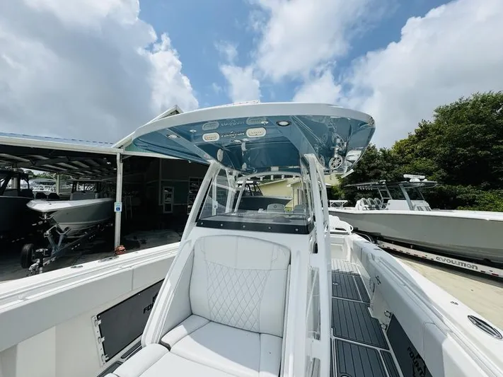  Yacht Photos Pics 2020 Fountain 38cc boat with white seating and blue canopy under a cloudy sky.
