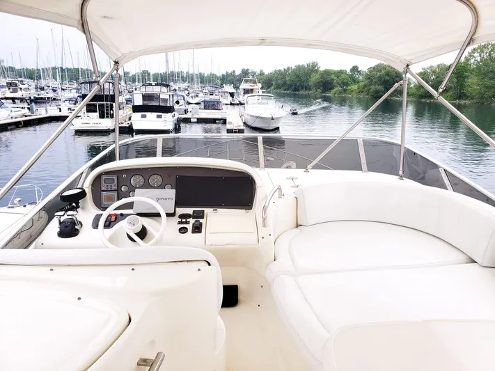  Yacht Photos Pics 2004 Azimut 62 Flybridge yacht helm with marina view, featuring white seating and controls.