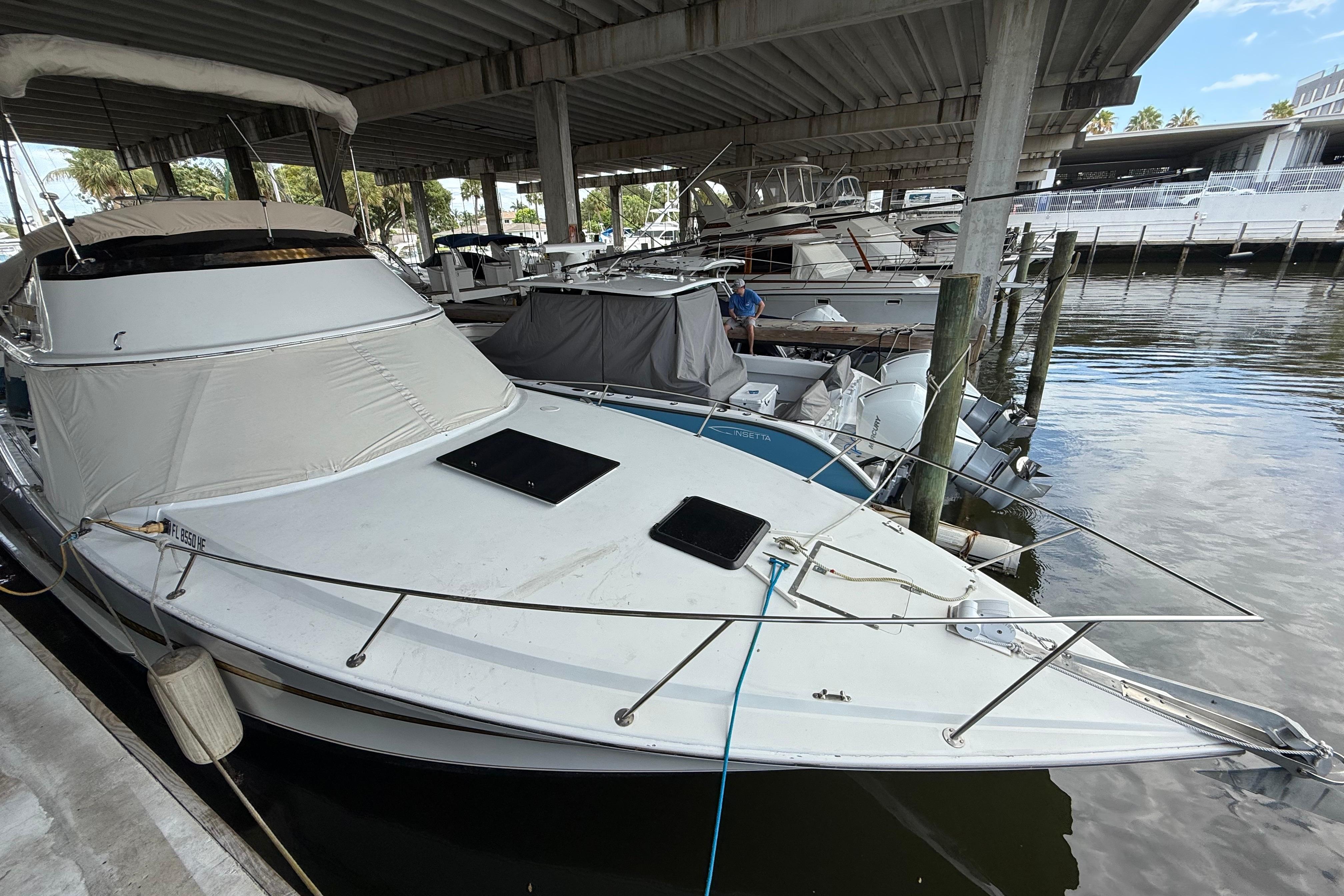 1984 Custom 38 boat docked under a covered marina, surrounded by other vessels.