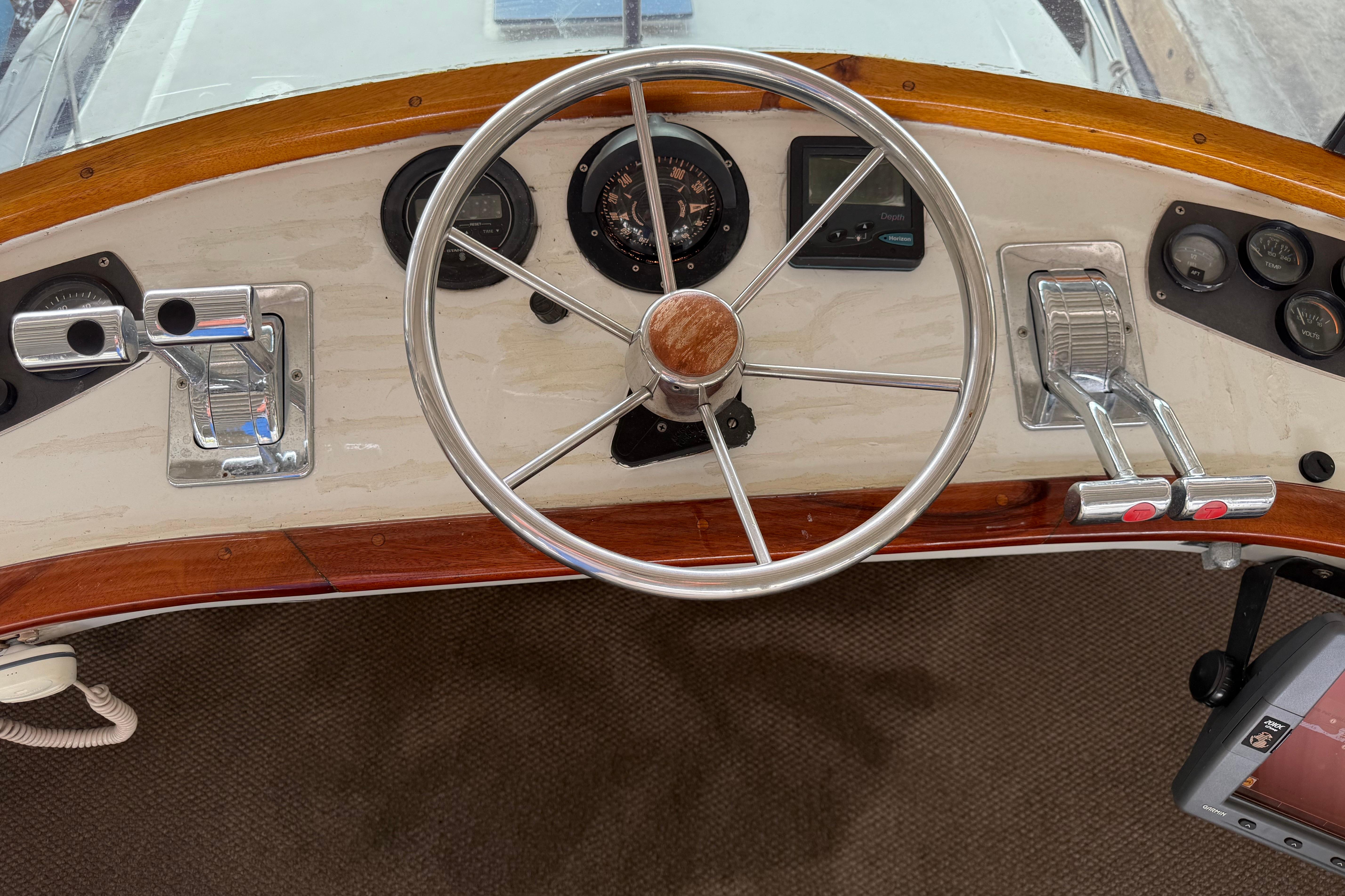 Steering wheel and controls of a 1984 Custom 38 boat, featuring wood accents.