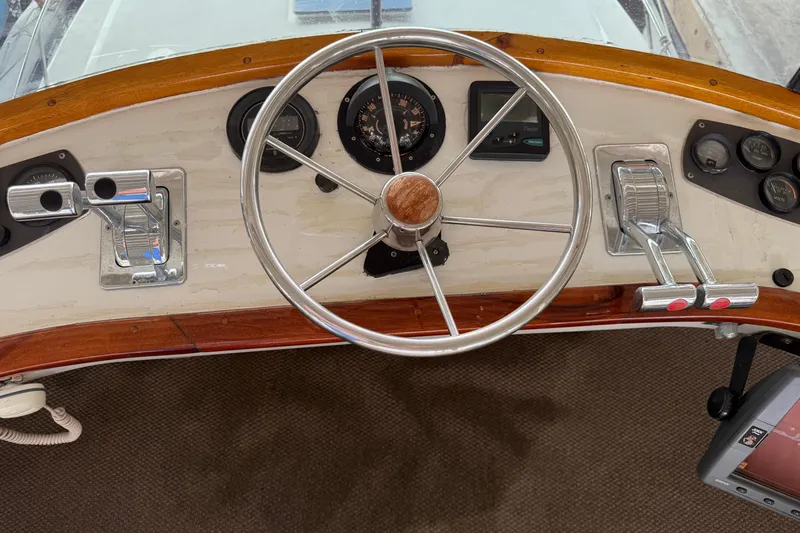 Caribbean Express Yacht Photos Pics Steering wheel and controls of a 1984 Custom 38 boat, featuring wood accents.