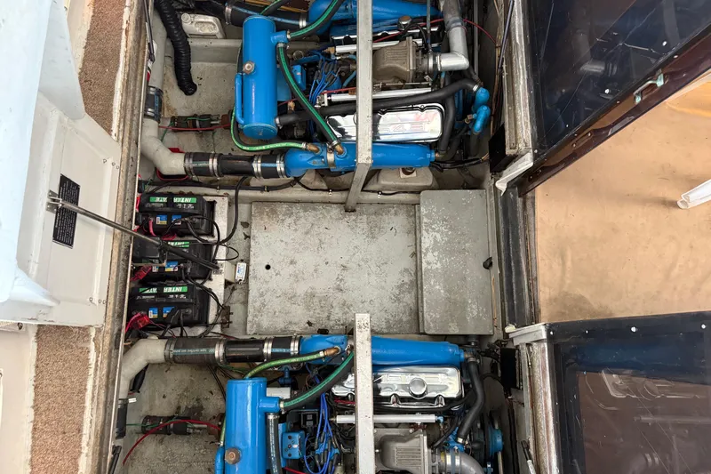 Caribbean Express Yacht Photos Pics Engine compartment of a 1984 Custom 38 boat with visible blue engines and batteries.