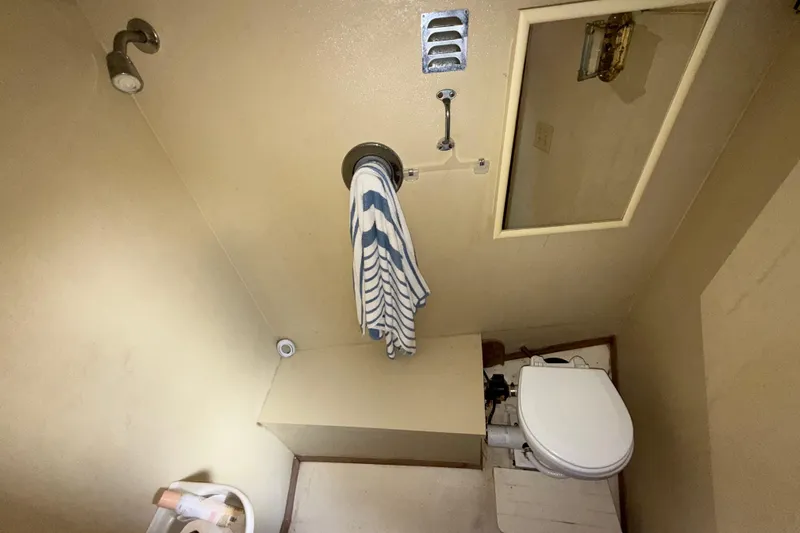 Caribbean Express Yacht Photos Pics Compact bathroom with shower, toilet, and striped towel in a 1984 Custom 38 model.