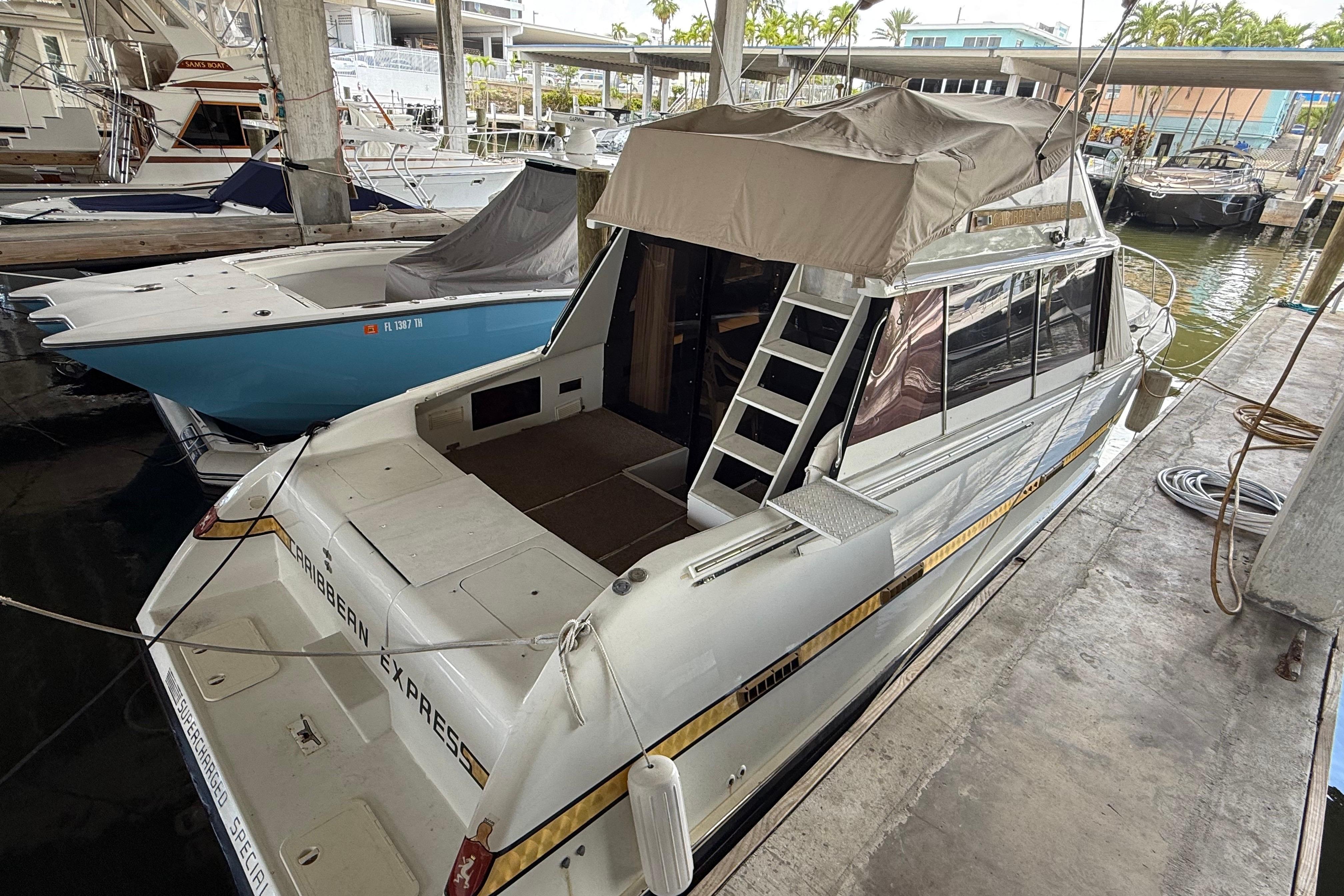 1984 Custom 38 boat docked in marina, featuring covered deck and ladder access.
