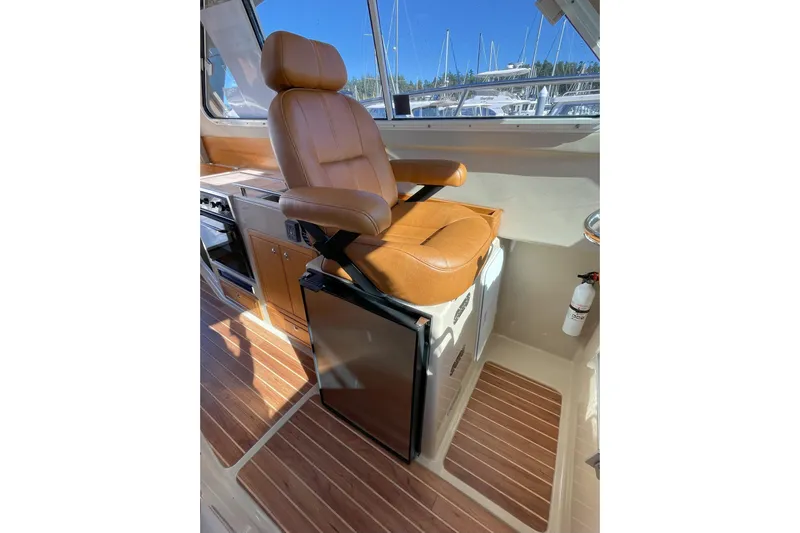 Sweet Jane Yacht Photos Pics Luxurious interior of 2015 Aspen C100 boat with leather captain's chair and wooden flooring.