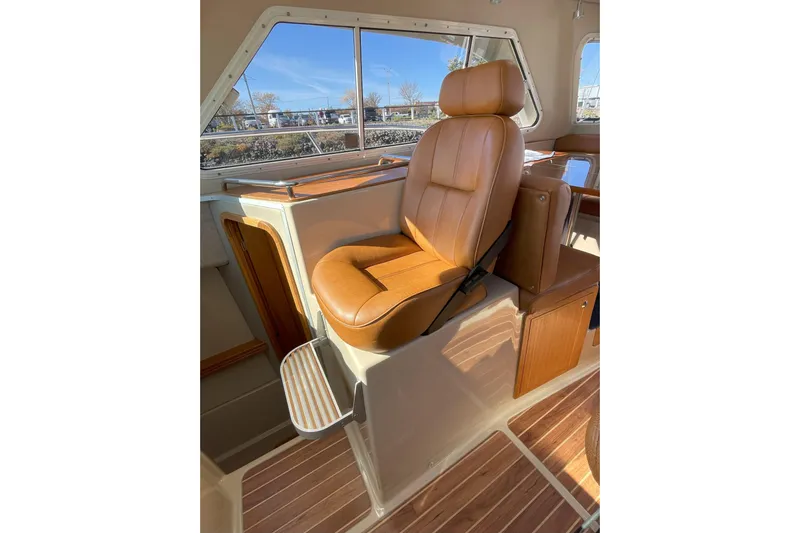 Sweet Jane Yacht Photos Pics Captain's chair in 2015 Aspen C100 boat, featuring tan leather and wood accents.