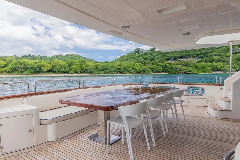 Camy Ed Yacht Photos Pics Luxurious 2006 Azimut 105 Grande yacht deck with dining area, overlooking serene waters and lush greenery.