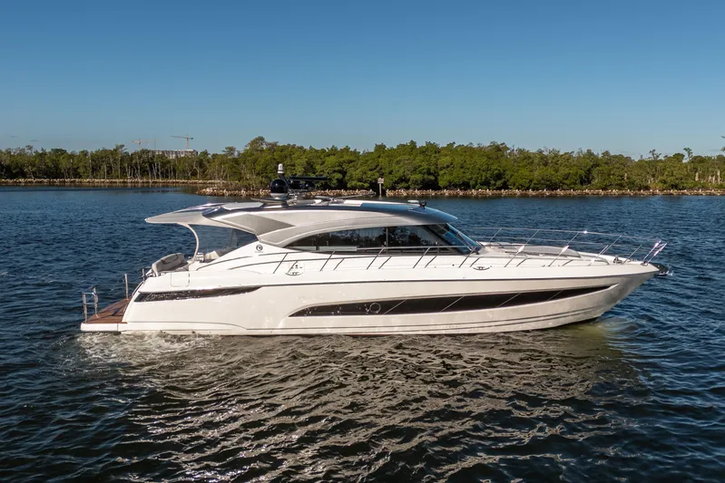 Water Dog Yacht Photos Pics 2024 Riviera 5400 Sport Yacht cruising on a serene lake with lush greenery.