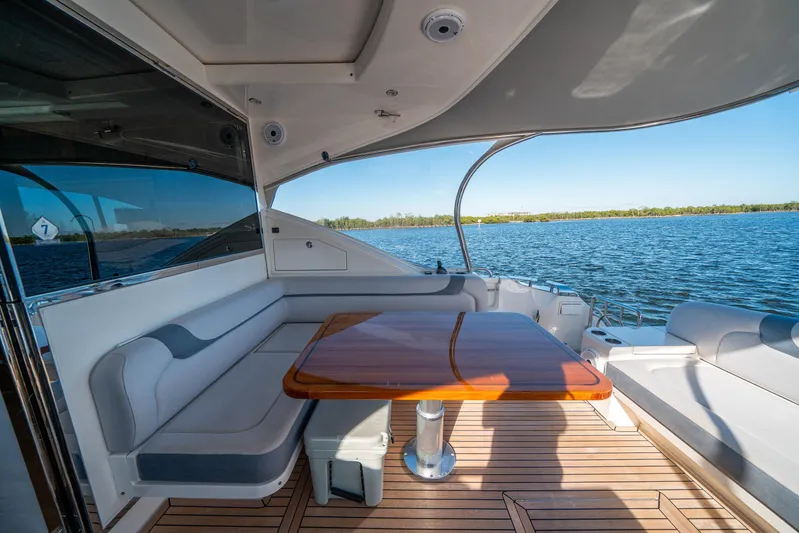 Water Dog Yacht Photos Pics 2024 Riviera 5400 Sport Yacht deck with seating and wooden table, overlooking serene water.