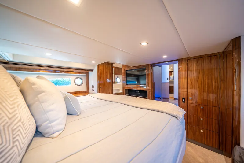 Water Dog Yacht Photos Pics Luxurious interior of 2024 Riviera 5400 Sport Yacht bedroom with wood paneling and modern amenities.