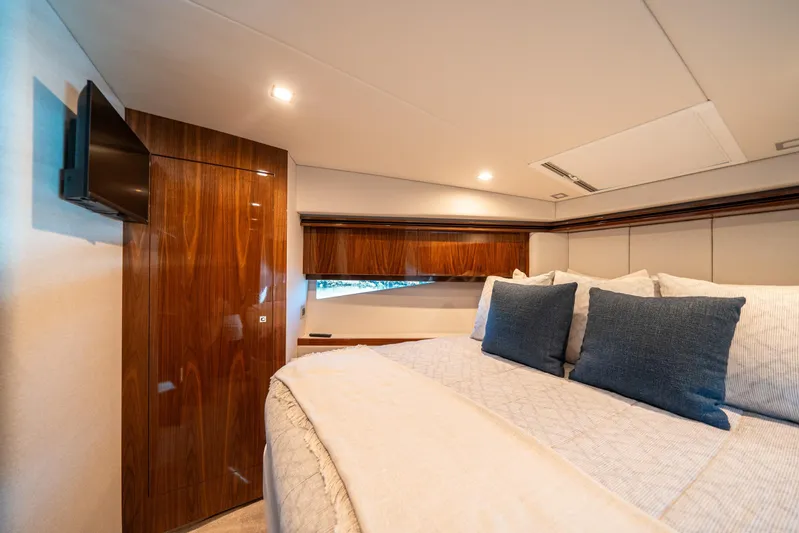 Water Dog Yacht Photos Pics Luxurious bedroom interior of 2024 Riviera 5400 Sport Yacht with elegant wood finishes.