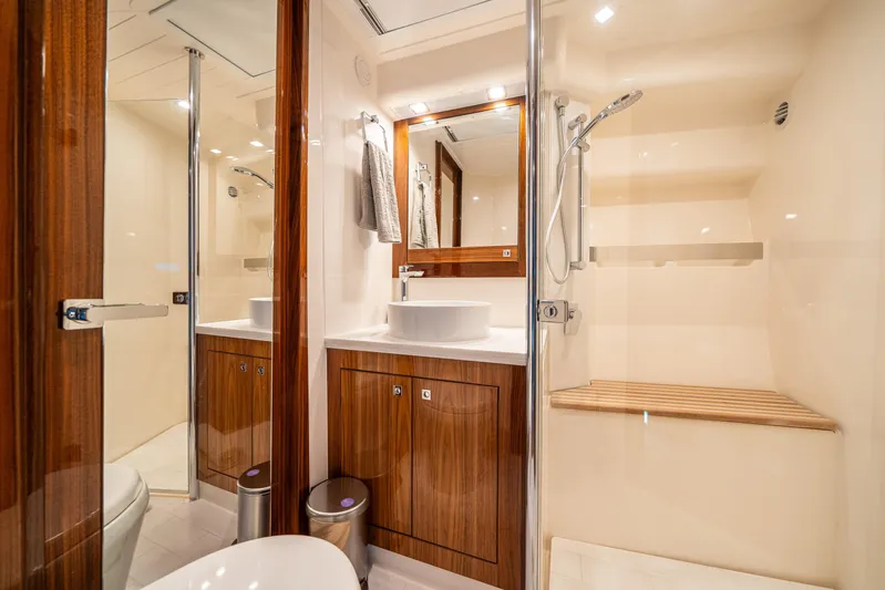 Water Dog Yacht Photos Pics Luxurious bathroom in 2024 Riviera 5400 Sport Yacht with wood accents and modern fixtures.