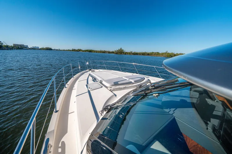 Water Dog Yacht Photos Pics 2024 Riviera 5400 Sport Yacht cruising on a serene lake under a clear blue sky.