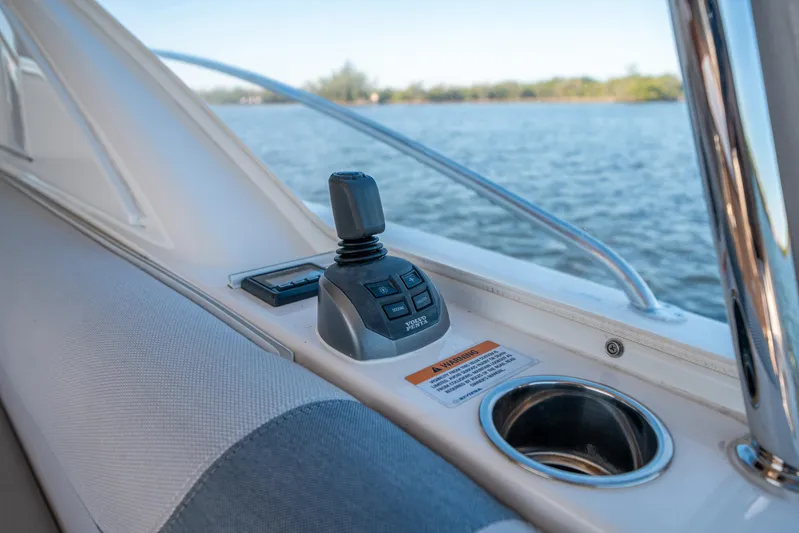 Water Dog Yacht Photos Pics 2024 Riviera 5400 Sport Yacht interior with joystick control and cup holder, overlooking water.