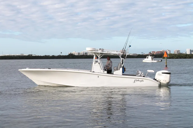  Yacht Photos Pics 2005 Yellowfin 31 Center Console boat on calm water, with fishing rods and cityscape background.