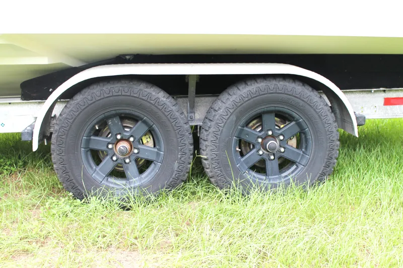  Yacht Photos Pics Trailer wheels of a 2005 Yellowfin 31 Open boat on grass.