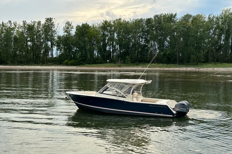  Yacht Photos Pics 2016 Grady-White Freedom 307 boat on calm water near a forested shoreline.