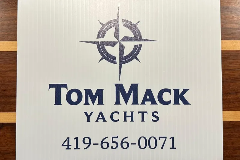 Yacht Photos Pics Tom Mack Yachts logo with contact number, featuring a nautical compass design.