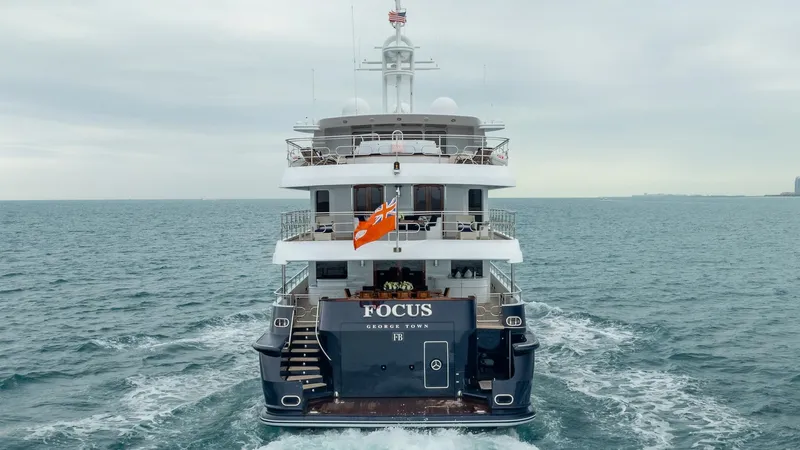 Focus Yacht Photos Pics North American Tri-Deck Motor Yacht, 2002, cruising on open sea with flag waving.