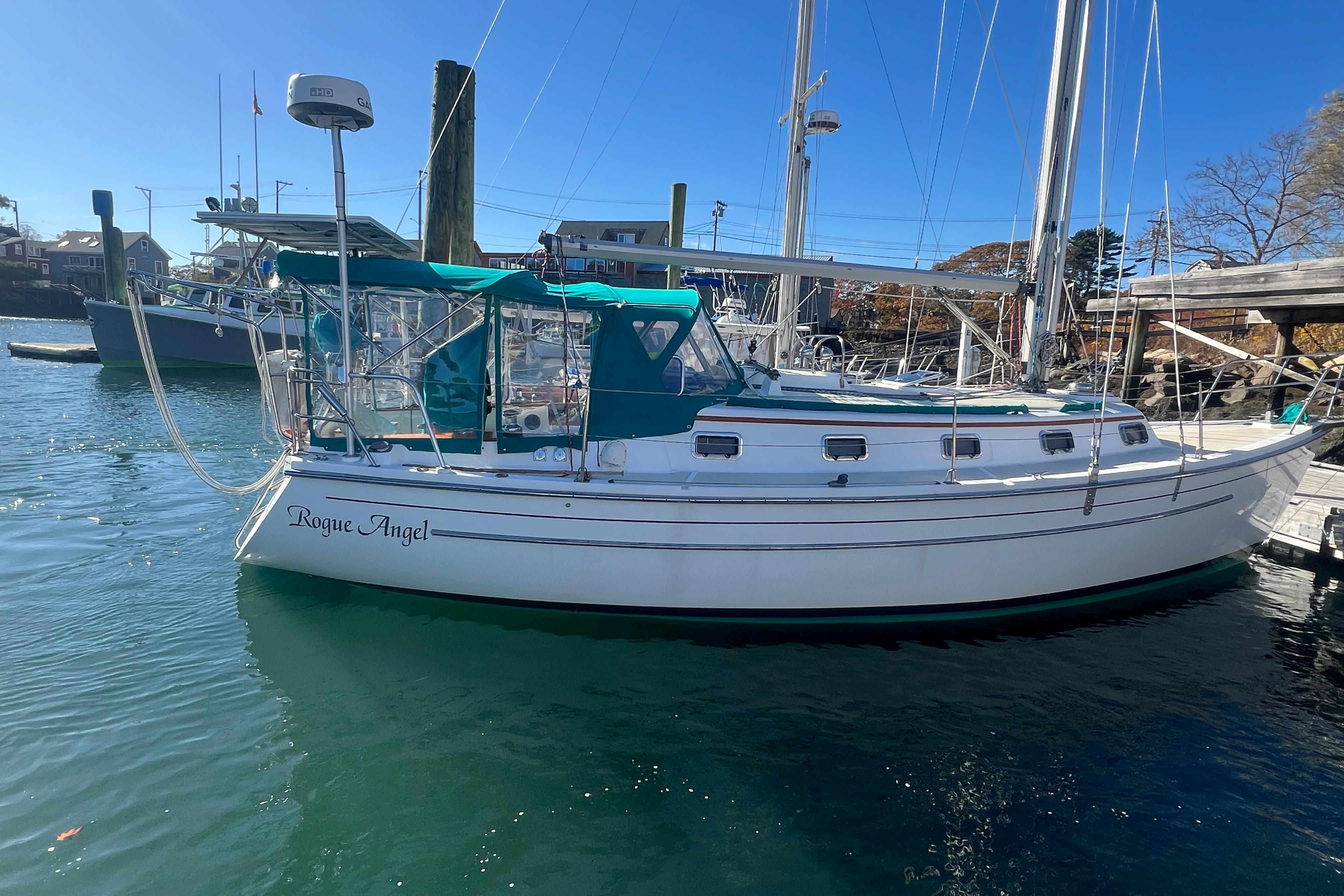 1993 Compac Sloop sailboat "Rogue Angel" docked in a sunny marina.